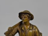 bronze figurine of a boy holding a baseball bat and ball