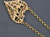 a close up of a gold necklace with a woven design on it