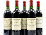 quatre bouteilles de vin rouge sont alignées sur une surface blanche