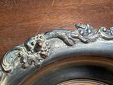 a silver plate with a lizard on it sitting on a table