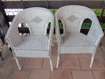 une paire de chaises en osier blanc posées sur une terrasse en briques