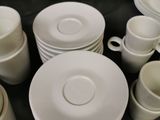 a lot of white plates and cups sitting on a table