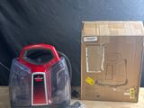 un aspirateur rouge et noir posé sur une table à côté d'une boîte