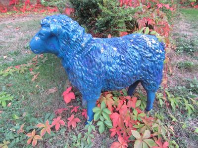 une statue bleue représentant un mouton debout dans l'herbe