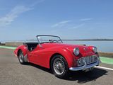 La voiture rouge est garée sur le bord de la route.