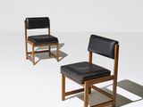 une paire de chaises en cuir noir et en bois posées sur une surface blanche