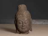 statue of a head of a buddha on a wooden table