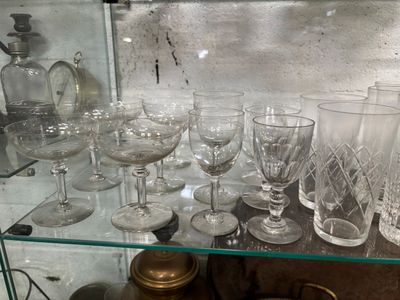 une étagère en verre sur laquelle sont posés de nombreux verres de toutes sortes