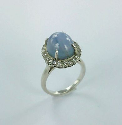 gros plan d'une bague avec une pierre bleue entourée de diamants