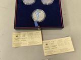 two silver coins are in a box with a ribbon around them