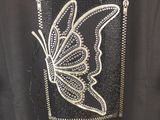 the back of a black shirt with a butterfly embroidered on it