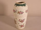 a white vase with pink flowers on it sitting on a table