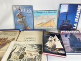 several books on a white surface with a ship in the background