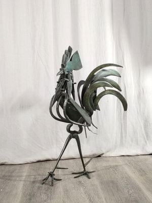 a metal rooster sculpture on a wooden floor