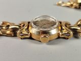 a gold watch with a chain around it on a table