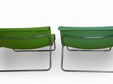 two green lawn chairs sitting next to each other on a white surface