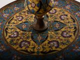 a gold vase sitting on top of a blue and gold plate