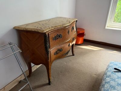 une commode dans un coin d'une pièce où se trouve une fenêtre