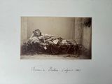 une vieille photo d'une femme assise sur un lit, recouverte d'une couverture