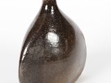 un vase brun posé sur une surface blanche
