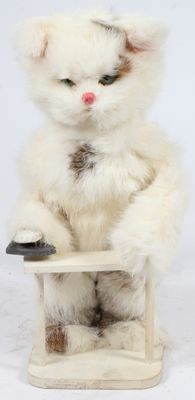un chat blanc assis sur une chaise, tenant une télécommande entre ses pattes