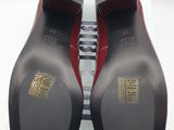 pair of black and red shoes with gold accents on a white surface