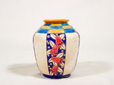 un vase bleu et jaune posé sur une surface blanche