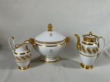 trois pièces en porcelaine blanche et dorée, ornées de bordures dorées