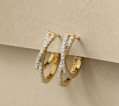 a pair of gold and diamond hoop earrings on top of a piece of paper
