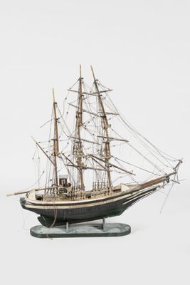 a model of a ship on a stand on a white surface