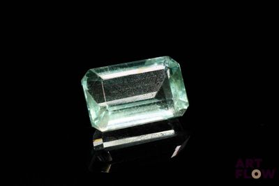 a close up of a green emerald stone on a black surface