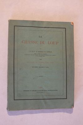 un vieux livre posé sur une table blanche, dont le titre est écrit en noir et rouge