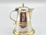 an antique silver coffee pot with a gold handle on a white surface