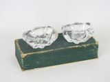 une paire de bougeoirs en verre transparent posés sur un livre vert