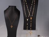 trois colliers et une croix exposés dans une vitrine