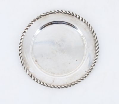 une assiette en argent entourée d'une corde torsadée sur un fond blanc