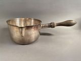 a silver bowl with a wooden handle on a table