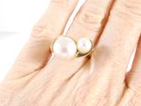 an image of a woman ' s hand holding a pearl and gold ring