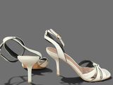 two pairs of white high heeled shoes on a gray surface