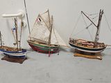 three small model boats on display on a table