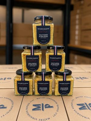 une pile de six pots de moutarde posée sur une boîte en carton