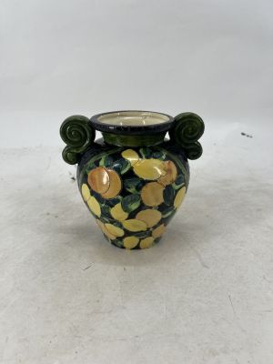 a small vase with lemons on it sitting on a table