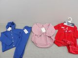 trois vêtements de bébé sont suspendus à un cintre posé par terre