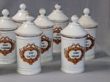 several white and gold canisters with labels on them on a table