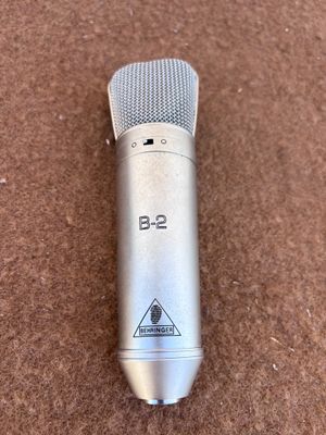 microphone argenté posé sur une moquette marron, avec une étiquette en noir et blanc