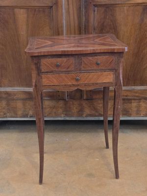 a small table with a drawer on it in front of a cabinet