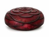 une boîte rouge ornée d'une fleur, posée sur un fond blanc