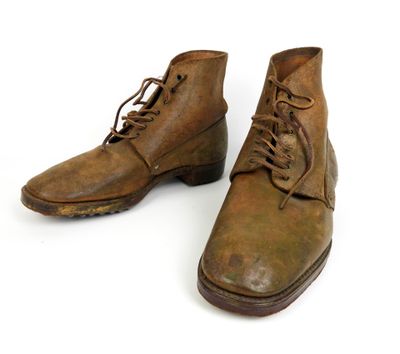 une paire de bottes en cuir marron à lacets posées sur une surface blanche