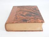 an old book with a brown cover sitting on top of a white table