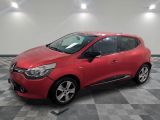 une voiture rouge est garée dans une pièce au sol en damier